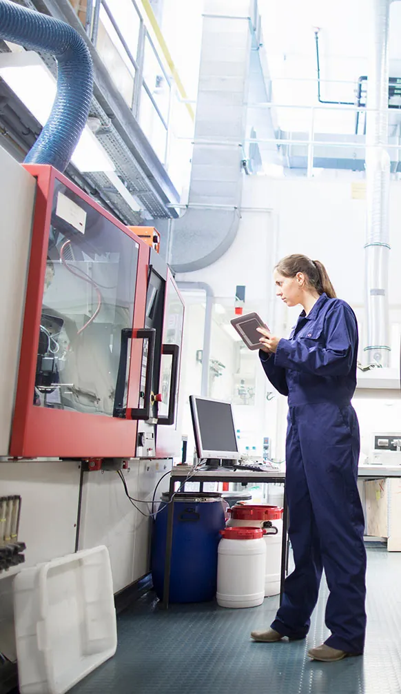 Mitarbeiter in Arbeitskleidung an einer Produktionsmaschine
