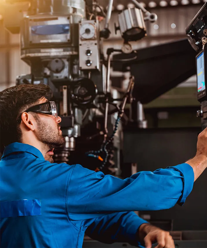 Mitarbeiter mit Schutzbrille bedient eine Fertigungsmaschine